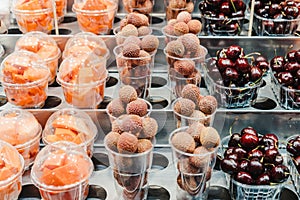 Fruit Salad arranged in plastic cups on a market stall with small fork inside, takeaway snack