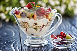 Fruit salad closeup with berries, yogurt and granola in a glass bow