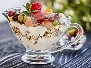 Fruit salad closeup with berries, yogurt and granola in a glass bow