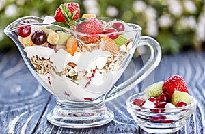 Fruit salad closeup with berries, yogurt and granola in a glass bow