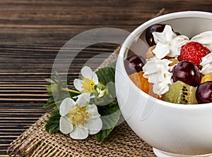 Fruit salad closeup with strawberry, orange, kiwi and cream on