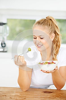 Fruit salad, eating or happy woman with a snack, morning breakfast or lunch diet in home kitchen. Smile, gut health or