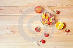 Fruit salad and fresh fruits on wooden table. Top view, copy space