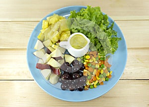 Fruit salad with fresh vegetables in a blue plate