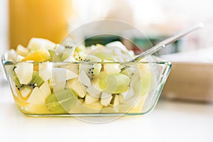 Fruit salad in glass bowl - healthy lunch idea - green grapes, banana, pear, kiwi fruit