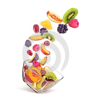 Fruit salad ingredients in the air in a glass bowl isolated