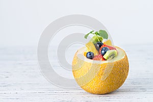 Fruit salad in melon on wooden table. Copy space