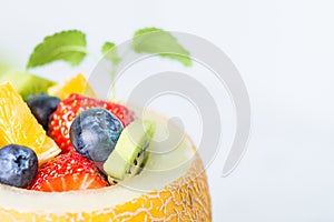 Fruit salad in melon on wooden table. Copy space