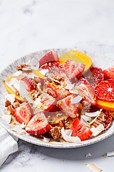 Fruit salad with persimmon, orange, strawberries, coconut chips and lemon zest