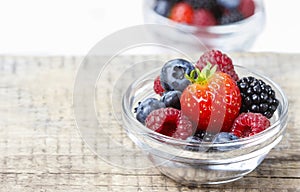 Fruit salad in small transparent bowl on wooden table