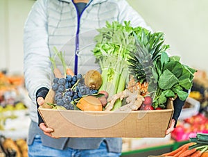 Fruit seller woman with different fruits and vegetables in shop  - Worker preparing fruit ecological paper basket - Vegetarian and
