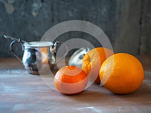 Fruit set of oranges and mandarin and a brass jar of sugar on a wooden table