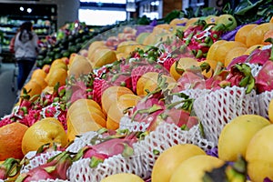 Fruit shop greengrocer display shelf with exotic fruits - mangooes, dragonfruits, oranges