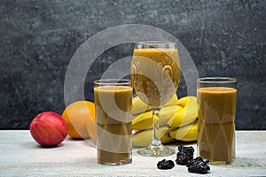 Fruit smoothie in glasses, with fruits on the table.