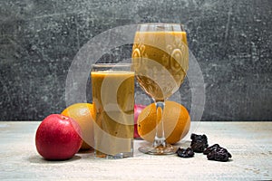 Fruit smoothie in glasses, with fruits on the table.