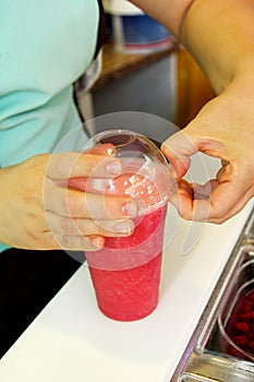 Fruit smoothie ready for sales in plastic cup with straw. Take away drinks concept. Fresh fruits juices at the public market.