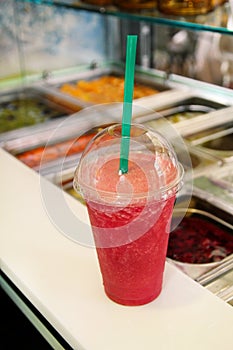 Fruit smoothie ready for sales in plastic cup with straw. Take away drinks concept. Fresh fruits juices at the public market.