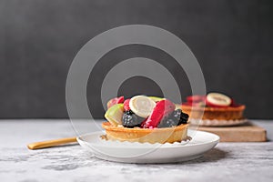 fruit tart or dessert topped with dragon fruit, blackberry, and apple