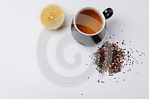 Fruit tea in a black mug, lemon segment and dried tea isolated on white background. Top view and copyspace