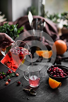 Fruit tea with honey in a large transparent teapot. Cranberries and lemons. Hot drink with pieces of fruit.