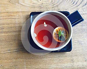 Fruit tea in a tea cup with pepmint and lemon on the wooden table in cafe for refreshness on tea time top view
