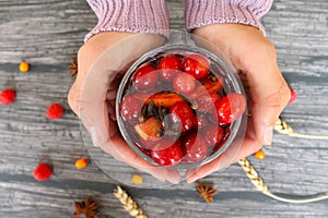 Fruit tea with wild berries in glass cup in woman hands