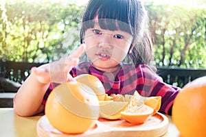 Fruit and Vegetable for Kids Concept. Little Cute 3-4 Years Old Girl with Sliced Orange on Wooden Plate