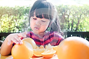 Fruit and Vegetable for Kids Concept. Little Cute 3-4 Years Old Girl with Sliced Orange on Wooden Plate