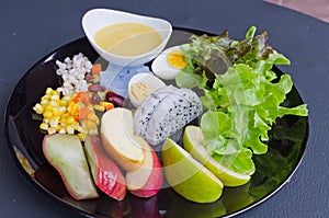 Fruit and vegetable salad on black plate