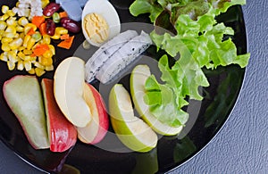 Fruit and vegetable salad on black plate