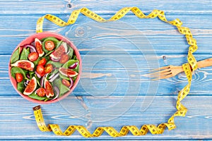 Fruit and vegetable salad, fork with tape measure, slimming and nutrition concept, copy space for text on boards