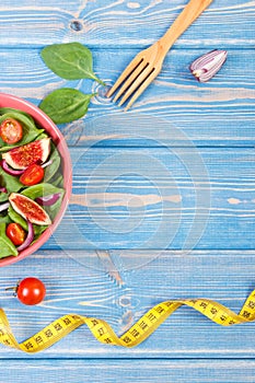 Fruit and vegetable salad, fork with tape measure, slimming and nutrition concept, copy space for text on boards