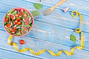 Fruit and vegetable salad, fork with tape measure, slimming and nutrition concept, copy space for text on boards