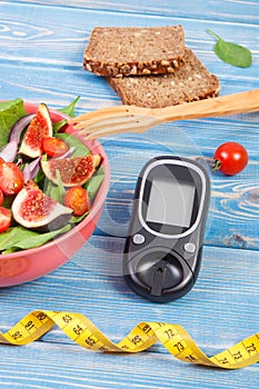 Fruit and vegetable salad and glucometer with tape measure, concept of diabetes, slimming and healthy nutrition