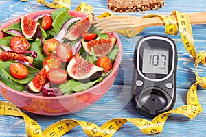 Fruit and vegetable salad and glucometer with tape measure, concept of diabetes, slimming and healthy nutrition