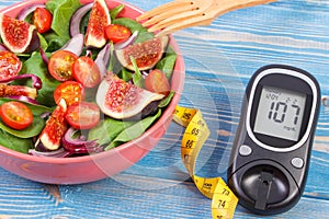 Fruit and vegetable salad and glucose meter with tape measure, concept of diabetes, slimming and healthy nutrition