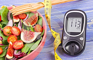 Fruit and vegetable salad and glucose meter with tape measure, concept of diabetes, slimming and healthy nutrition