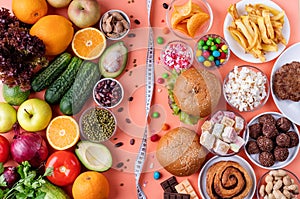 Fruit and vegetables vs sweets and fast food top view flat lay on orange background