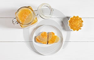 Fruit yellow jam on a white wooden background. Heart shaped delicious toast on a plate. Top view, flat lay