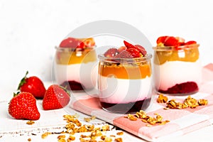 Fruit yogurt berry with muesli and fresh strawberries, on a white wooden background