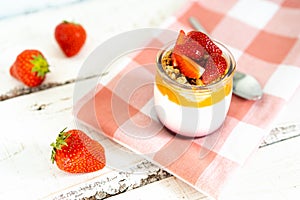 Fruit yogurt berry with muesli and fresh strawberries, on a white wooden background