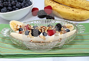 Fruit and yogurt fruit salad with granola and nuts styled as a banana split