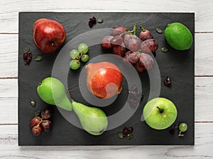 fruits background green and red color composition on dark stone slake plate and white wood table. Summer abstract creative trendy