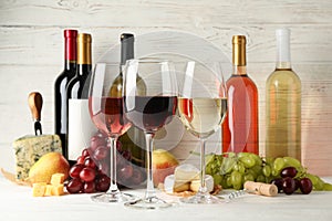 Fruits, cheese, bottles and glasses with different wine on white background