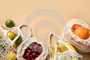 Fruits and citrics in eco-friendly mesh bags on beige background. Zero waste shopping.