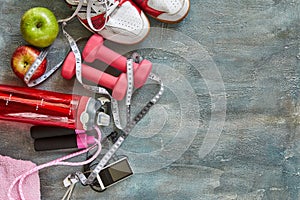 Fruits, dumbbells, a bottle of water, rope, sneakers and a meter on a blue with divorce background