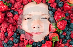 Fruits for kids. Assorted mix of strawberry, blueberry, raspberry, blackberry background. Berries closeup near kids face