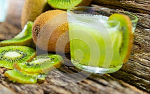 Fruits and Kiwi juice fresh and in halves on a woody background