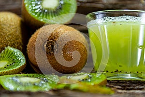 Fruits and Kiwi juice fresh and in halves on a woody background