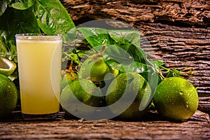 Fruits and passion fruit juice Passiflora edulis amid green leaves on wooden background